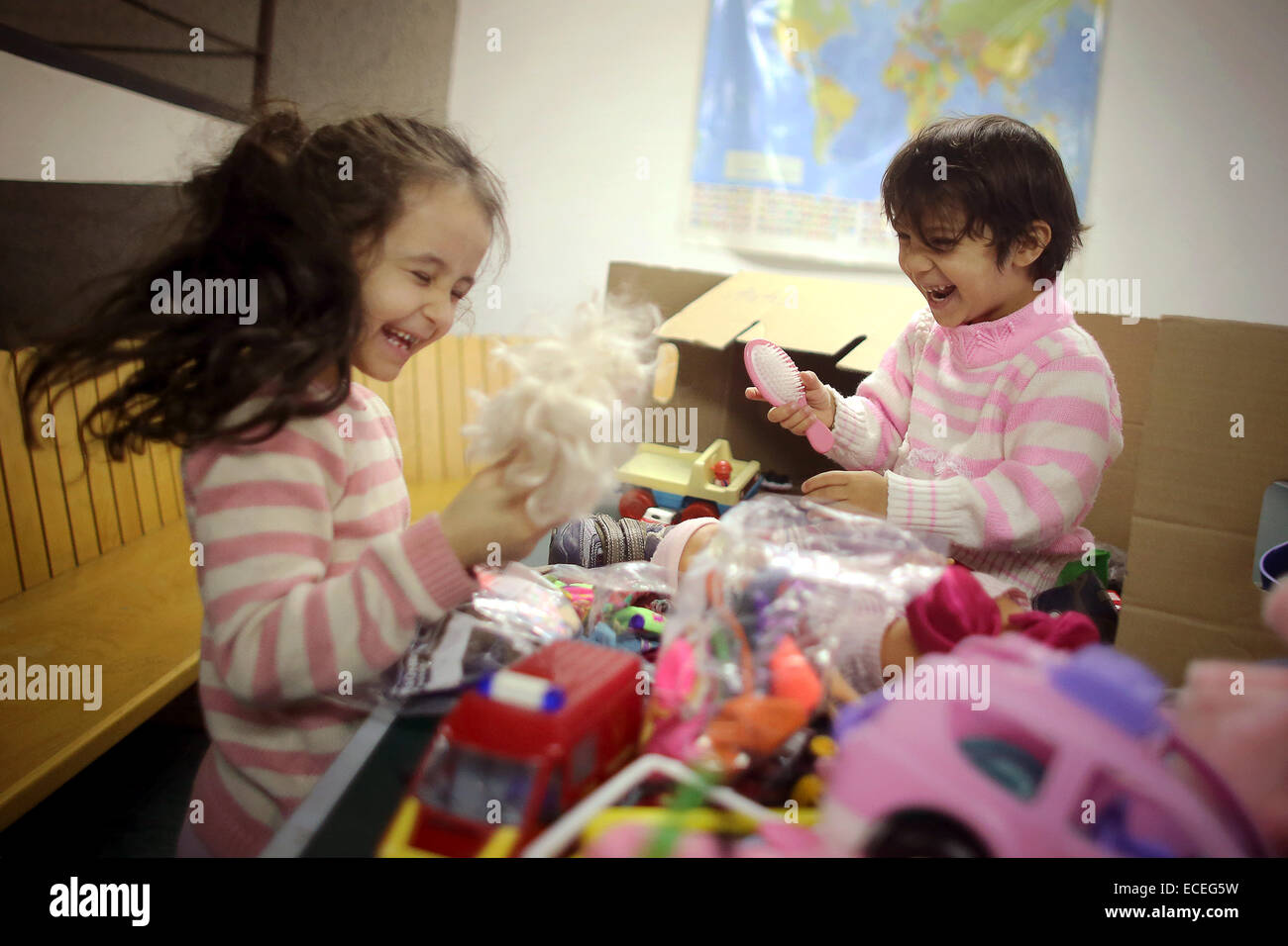 Mainz, Germany. 12th Dec, 2014. Hatice (L) and Oueza (R, children of Russian refugees) play with donated toys with their mother Jurida in the Alte Feuerwache in Mainz, Germany, 12 December 2014. Employees of the Rhineland-Palatinate State Office for Criminal Investigations donated to the refugees. Photo: FREDRIK VON ERICHSEN/dpa/Alamy Live News Stock Photo