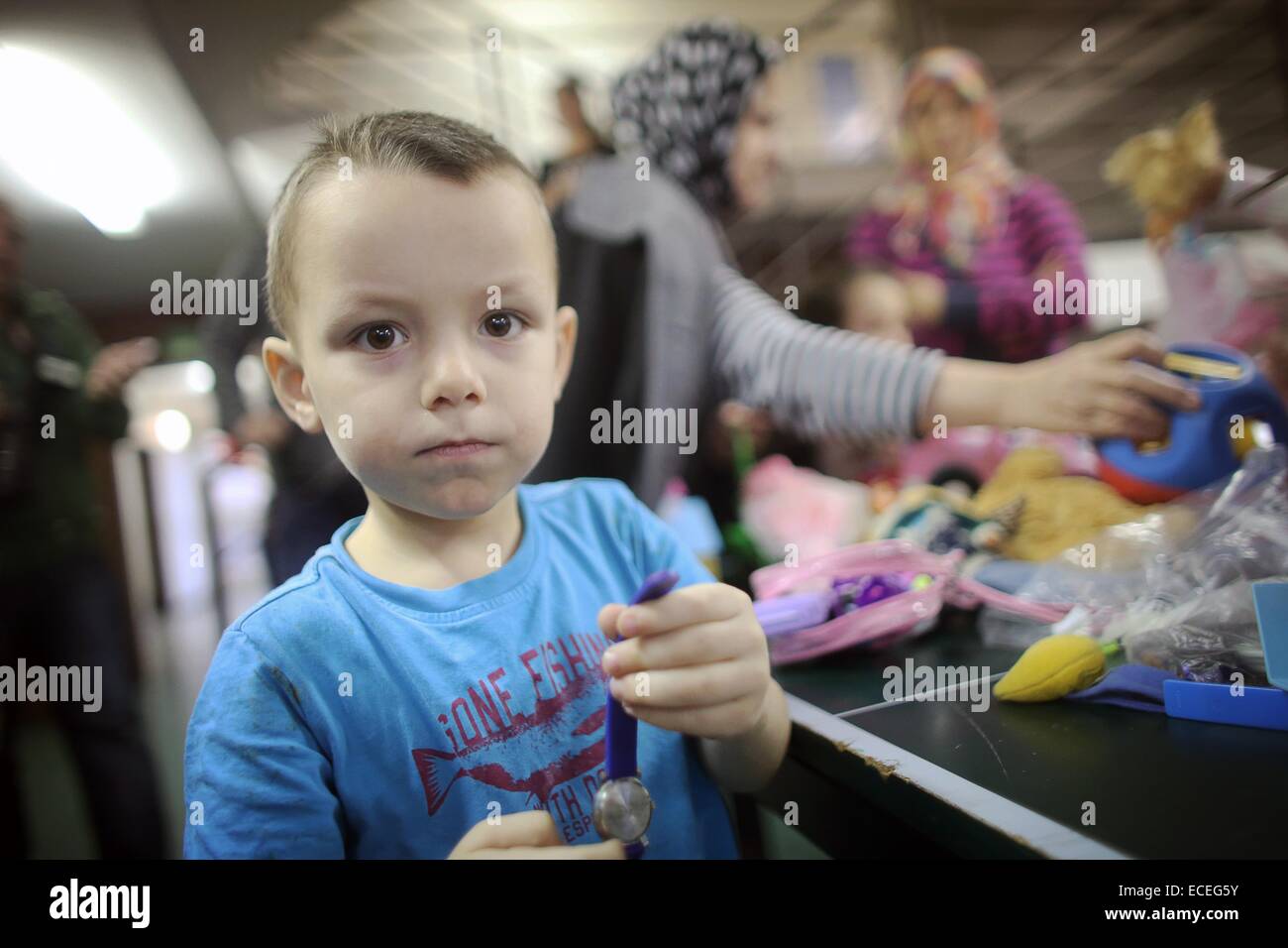 Mainz, Germany. 12th Dec, 2014. Ahmet (son of Russian refugees) plays with donated toys in the Alte Feuerwache in Mainz, Germany, 12 December 2014. Employees of the Rhineland-Palatinate State Office for Criminal Investigations donated to the refugees. Photo: FREDRIK VON ERICHSEN/dpa/Alamy Live News Stock Photo