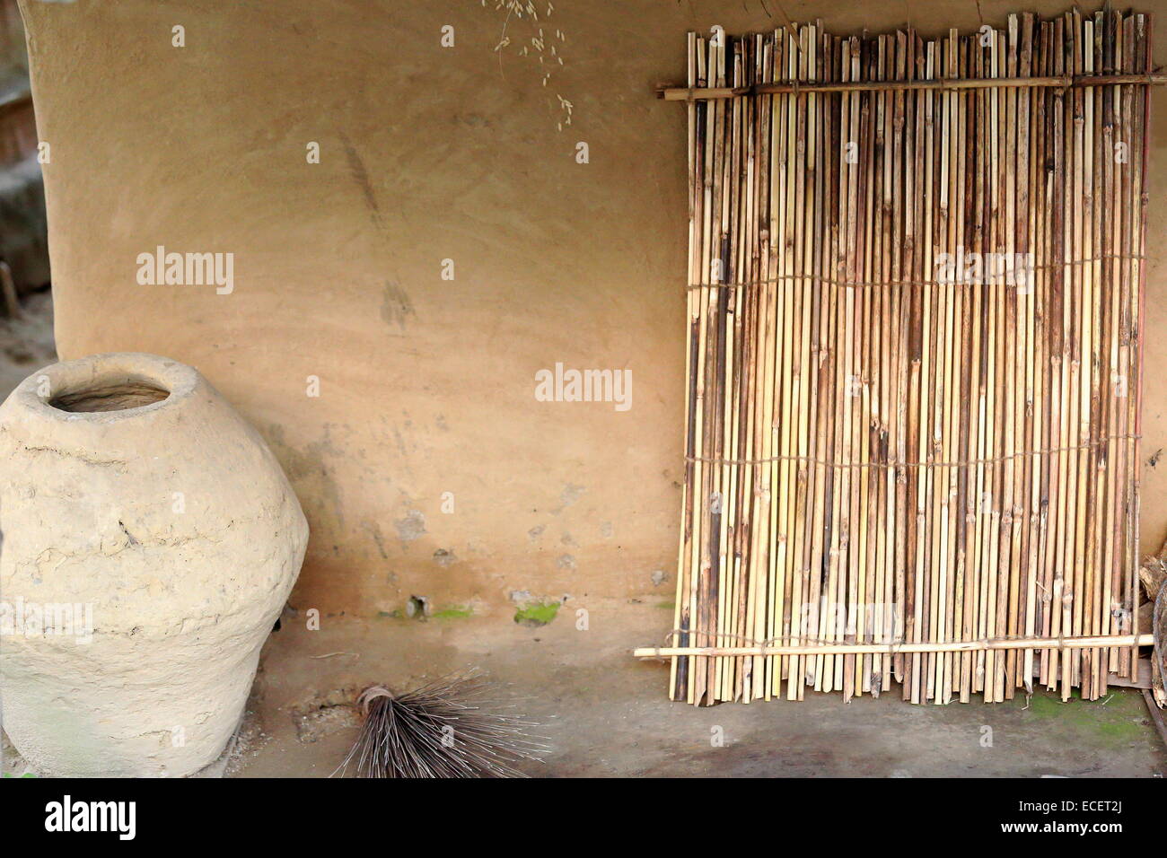 Big terracotta vessel and reed fence leaning on the mud finished wall ...