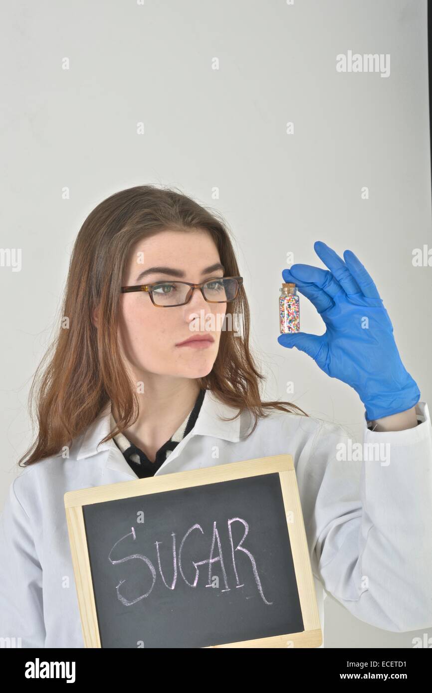 Nutritionist holding a small glass bottle full of colored sweets Stock Photo