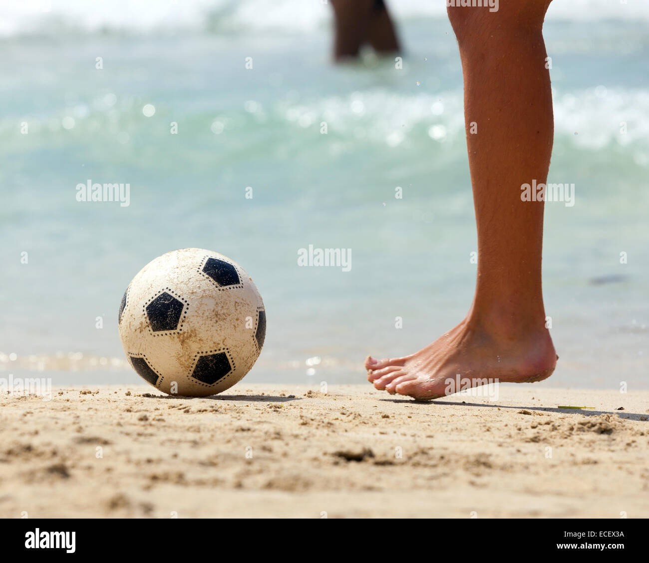 Close up of male foot playing football on sand. Stock Photo