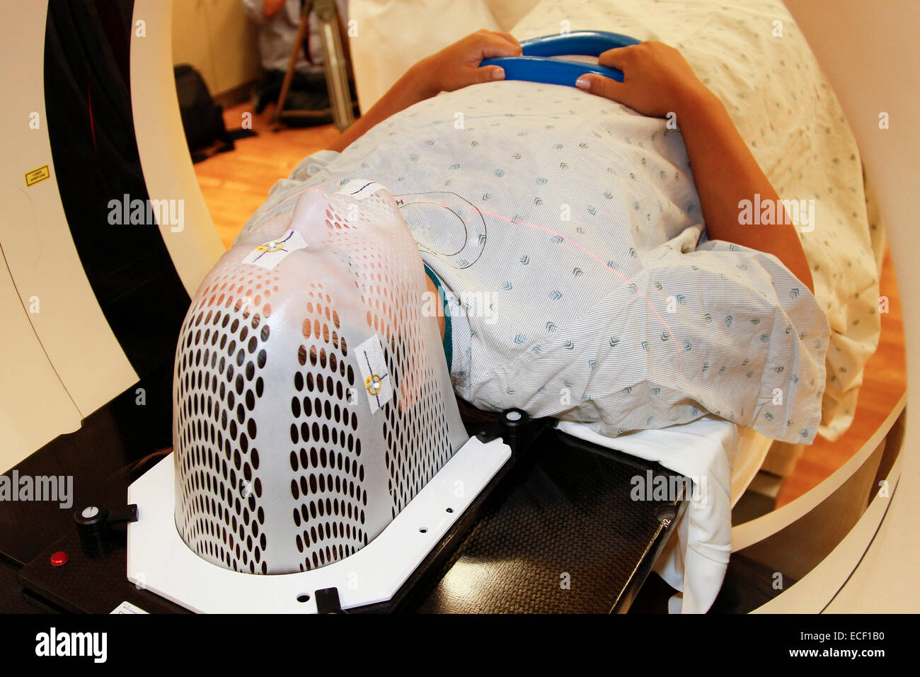 A patient model wearing a short face mask is positioned in a computed tomography (CT) scanner to obtain images of a tumor before Stock Photo