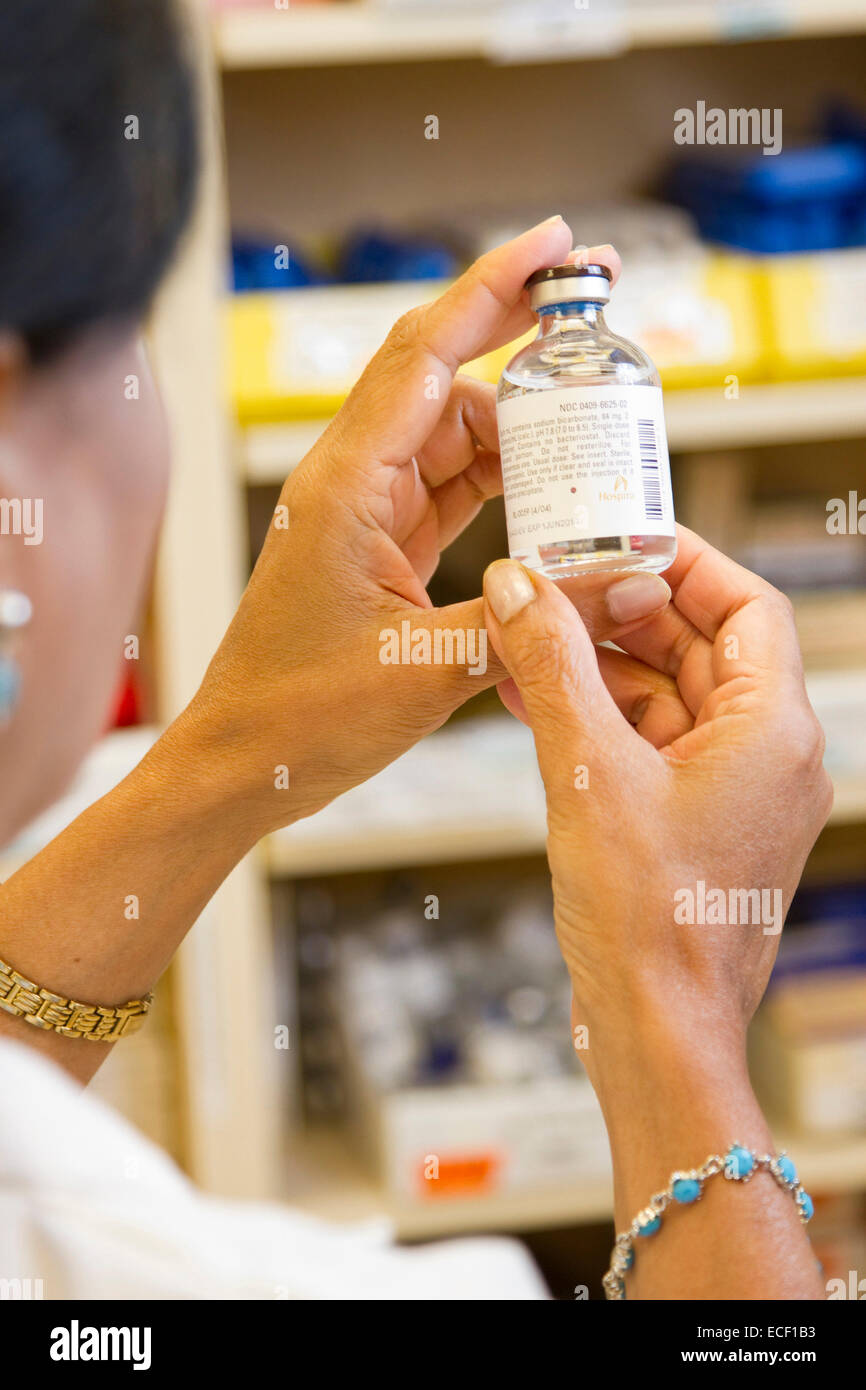 A female pharmacist examining a vial in a pharmacy. Stock Photo