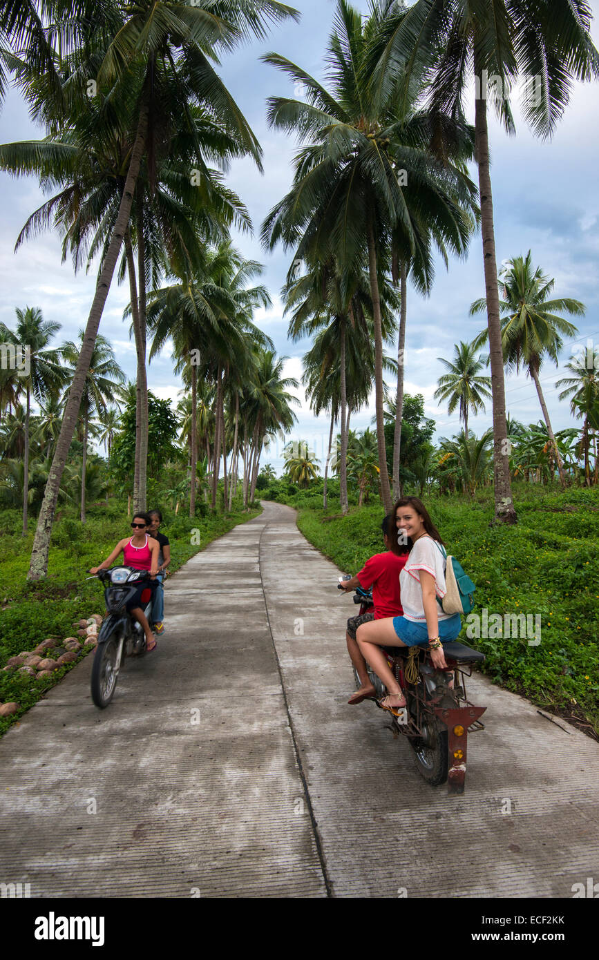 Woman riding a motorcycle taxi on a rural road in the Philippines Stock Photo