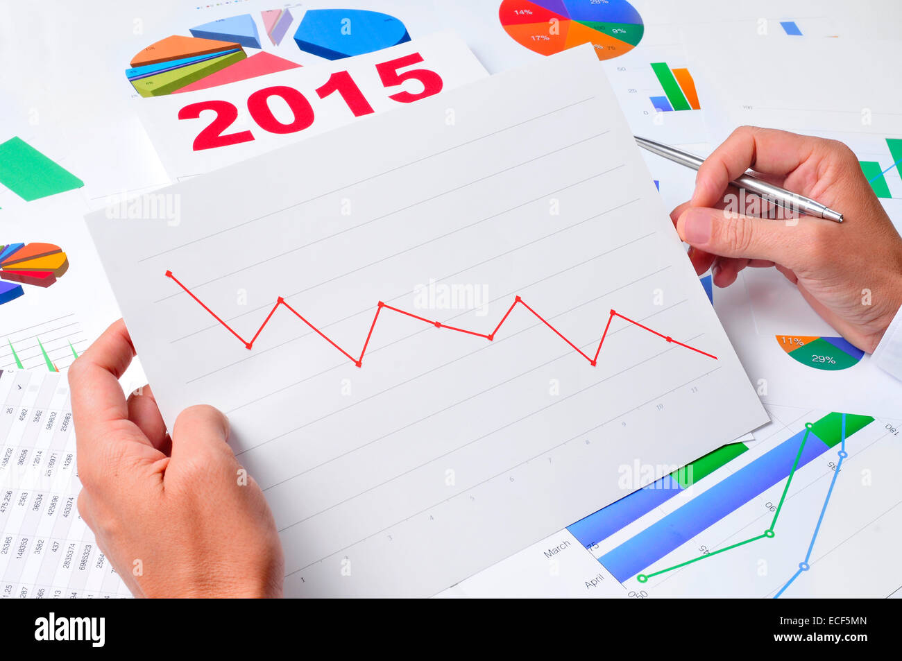 businessman in his office desk observing a chart with a downward trend, with a 2015 calendar in the background Stock Photo