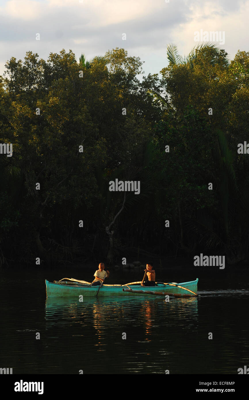 Boys on outrigger boat in Mangroves Stock Photo
