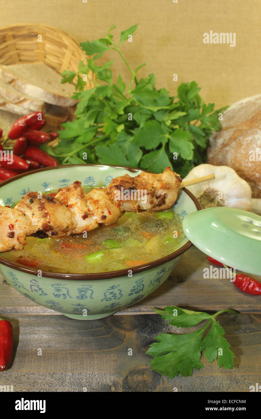 Chicken consomme with chicken skewers, vegetable and greens Stock Photo