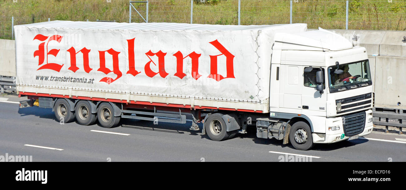 Side view left hand drive Austrian haulage business white lorry truck & driver soft sided curtain trailer England advert driving along UK motorway Stock Photo
