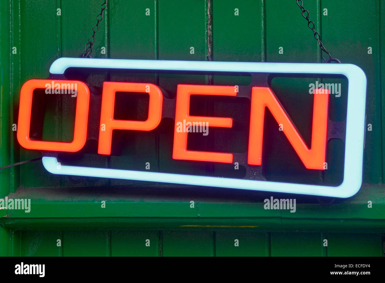 Close up of red Neon electric 'Open' sign hanging on the side of a small café business building London England UK Stock Photo