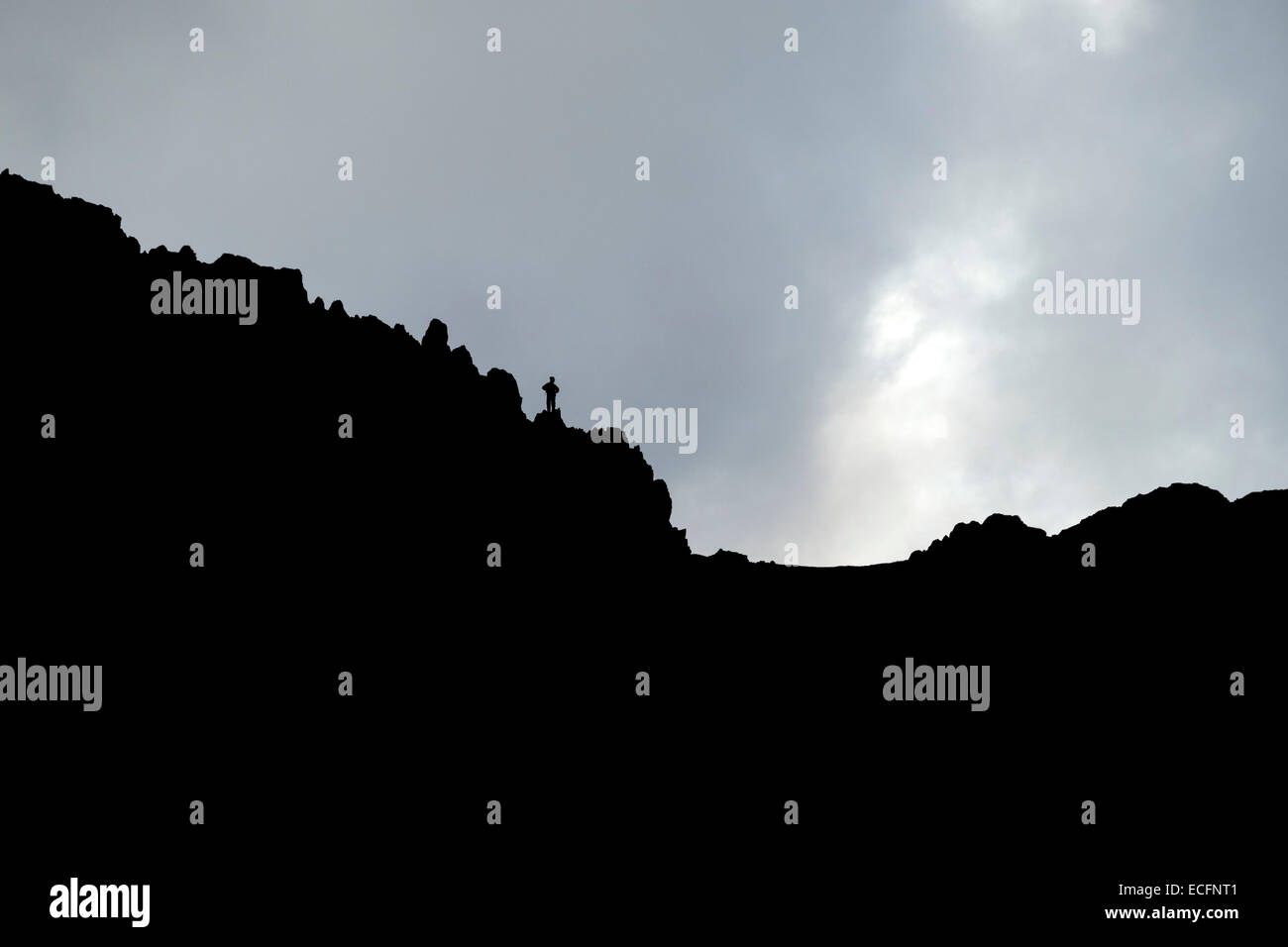 Silhouette of lone walker on Striding Edge mountain ridge, Helvellyn, Lake District, Cumbria, England, UK Stock Photo