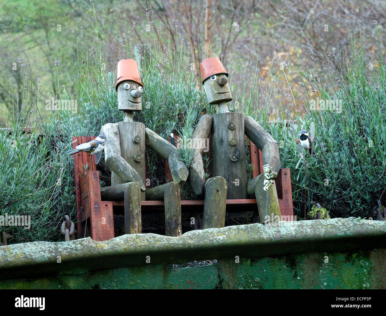 Wooden models of Bill and Ben Flower Pot men sitting on bench in garden. Stock Photo