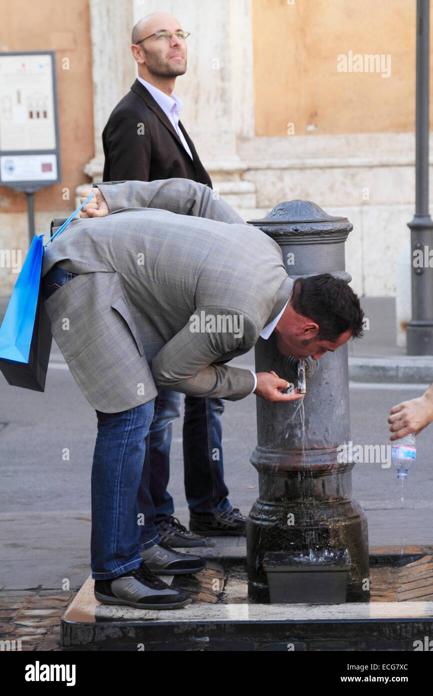 An adult man person drinking water from the fountain tap in the street, Rome, Italy Stock Photo