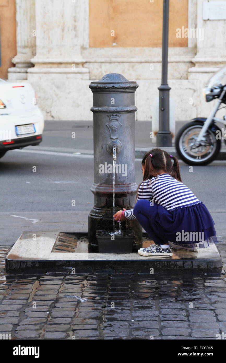 A little girl drinking water from the fountain tap in the street, Rome, Italy Stock Photo