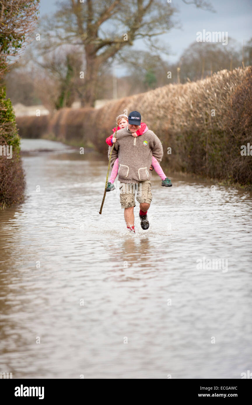 Atcham, Shropshire, UK. 14th December, 2014. James Healey, Chartered Civil Engineer from Cross Houses, Shropshire carries his eight-year-old daughter Isabella home through a flooded lane. Credit:  Graham M. Lawrence/Alamy Live News. Stock Photo