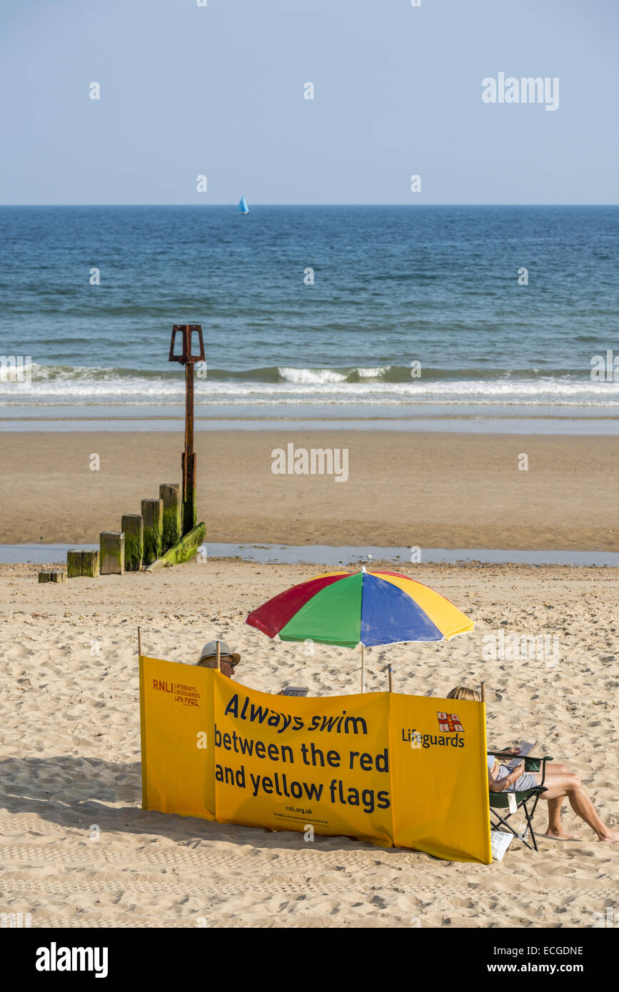 A RNLI Lifeguards windbreak on the beach at Poole, Dorset, UK warns swimmers to Always swim between the red and yellow flags Stock Photo