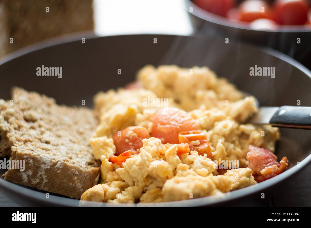 A plate of fresh scrambled eggs on a white wooden table with healthy ...