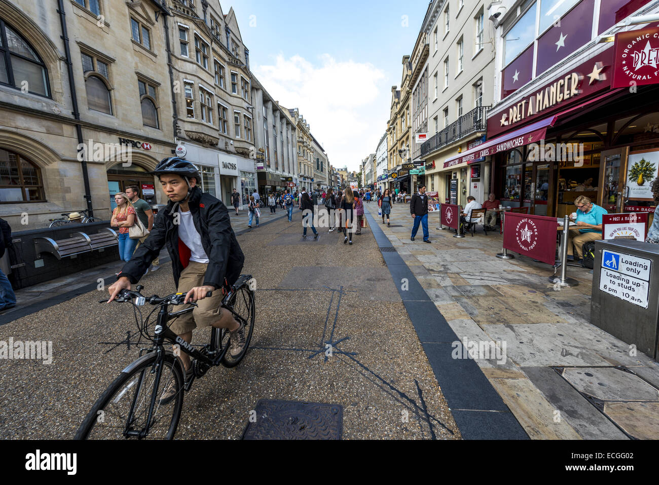 A cyclist rides down Cornmarket Street, a pedestrianised shopping street in Oxford, UK Stock Photo