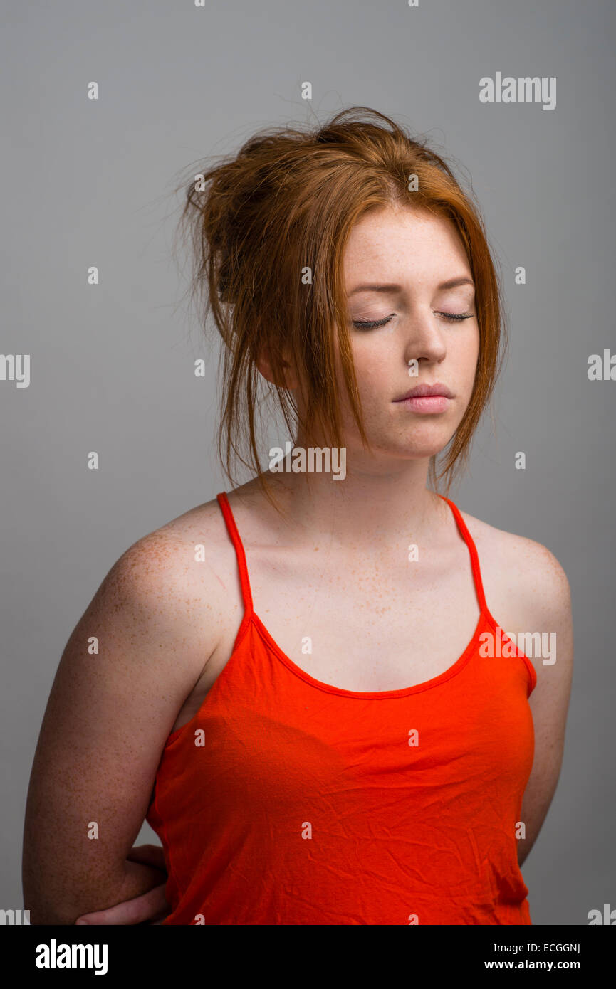 A ginger haired freckled skinned 16 17 18 year old slim caucasian teenage british girl eyes closed daydreaming meditating UK Stock Photo
