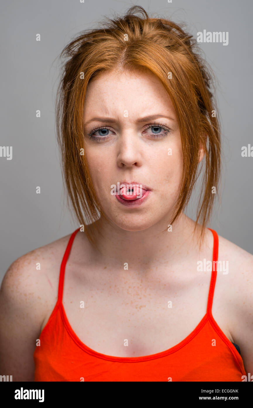 A ginger haired freckled skinned 16 17 18 year old slim caucasian teenage british girl rolling her tongue UK Stock Photo