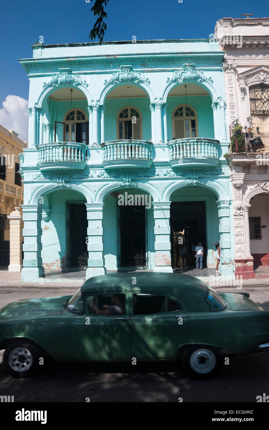 An antique car passes a colorful example of Spanish colonial architecture on the Prado (Paseo de Marti) in Havana Cuba Stock Photo