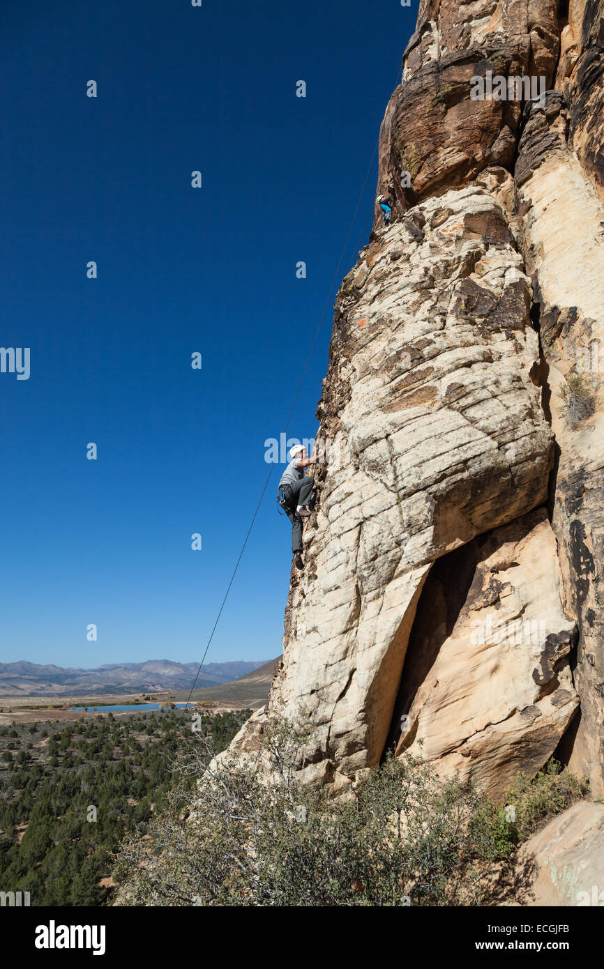 young man climbing a sandstone cliff with all the necessary safety gear ...