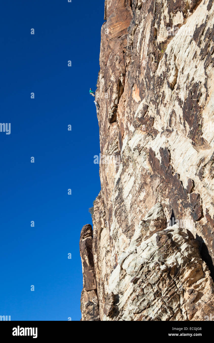 young man climbing a sandstone cliff with all the necessary safety gear Stock Photo