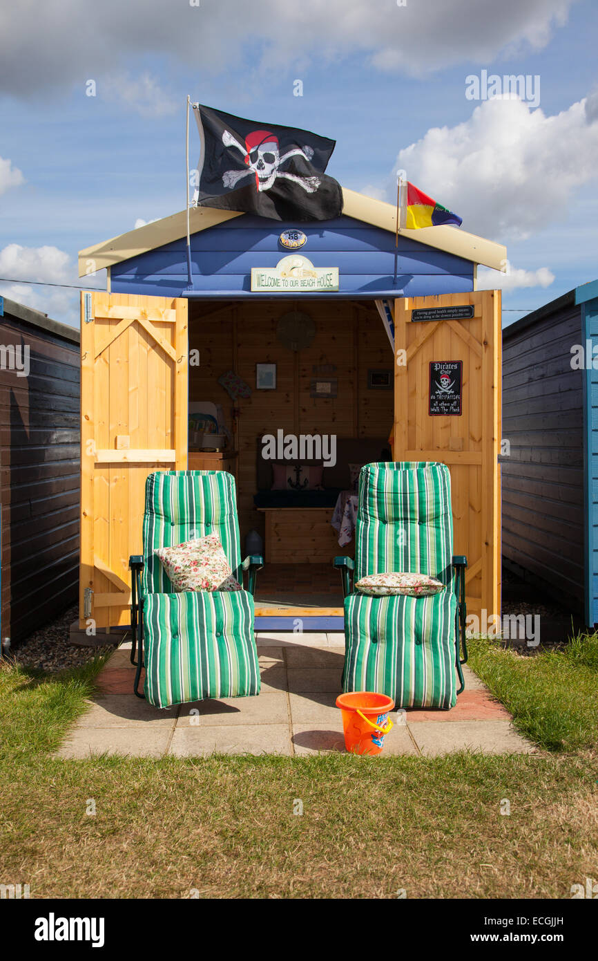 Beach hut with two reclining garden chairs, beach hut has a pirate flag flying from the roof
