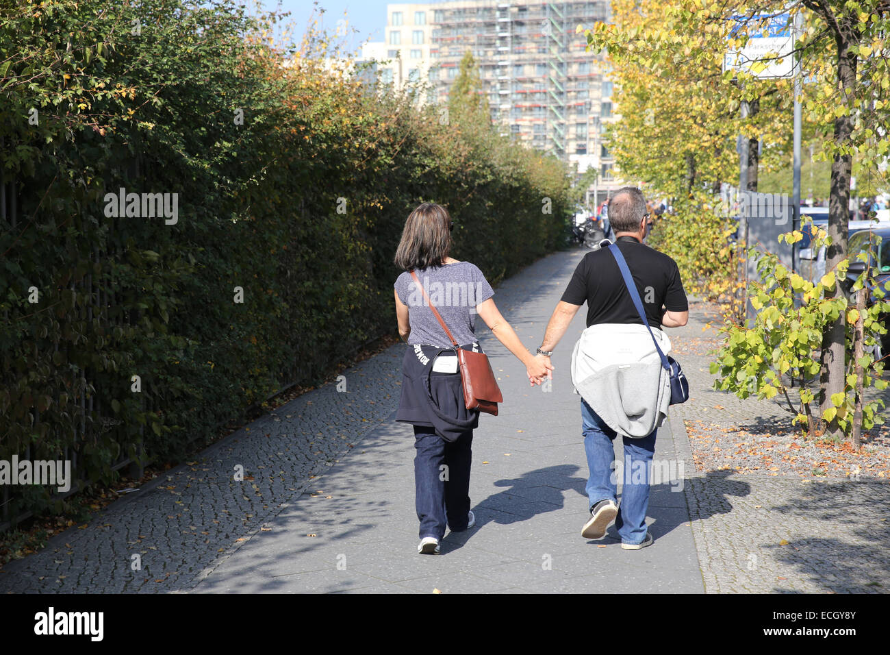 man woman hold hands walk street outdoor europe germany berlin Stock Photo