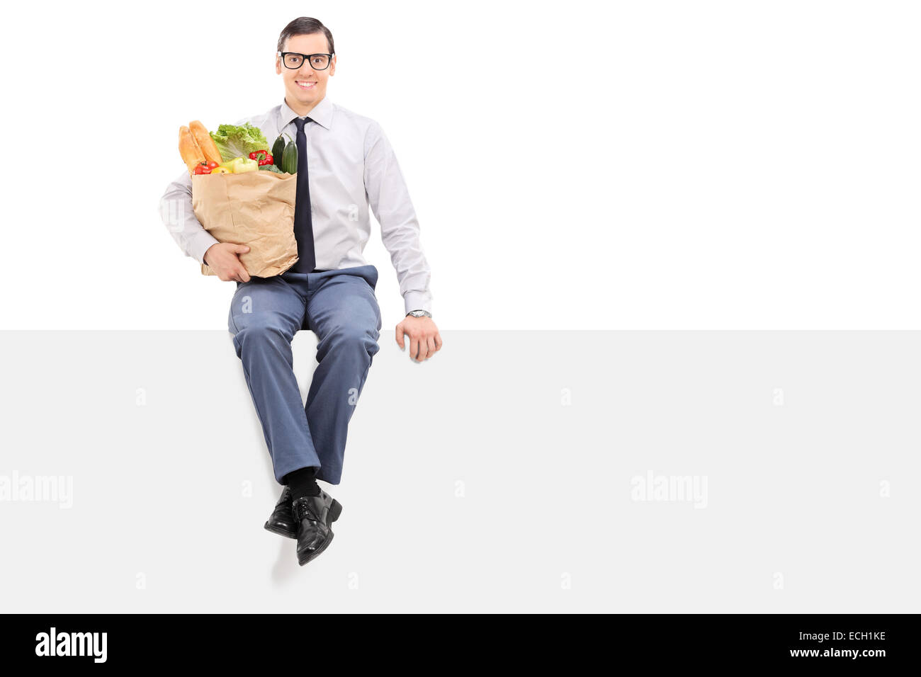 Man holding bag of groceries seated on panel isolated on white background Stock Photo Alamy