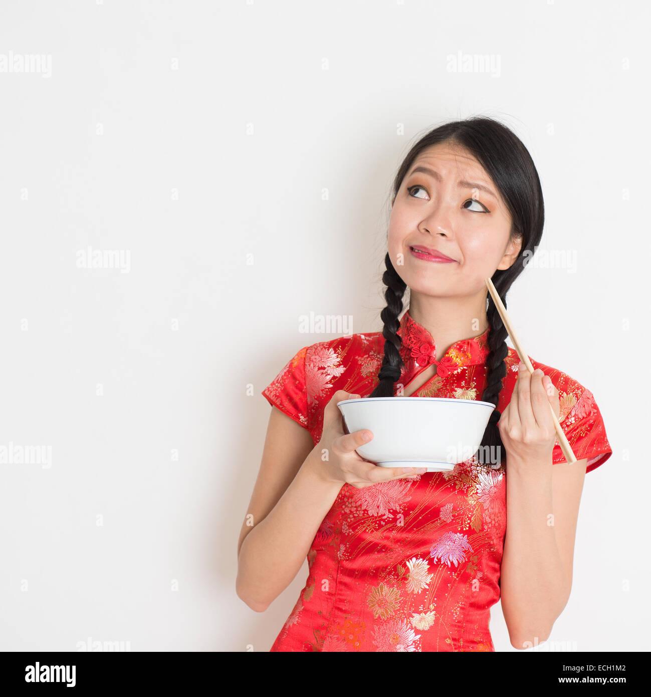 Asian Chinese female eating using chopsticks holding rice bowl, in
