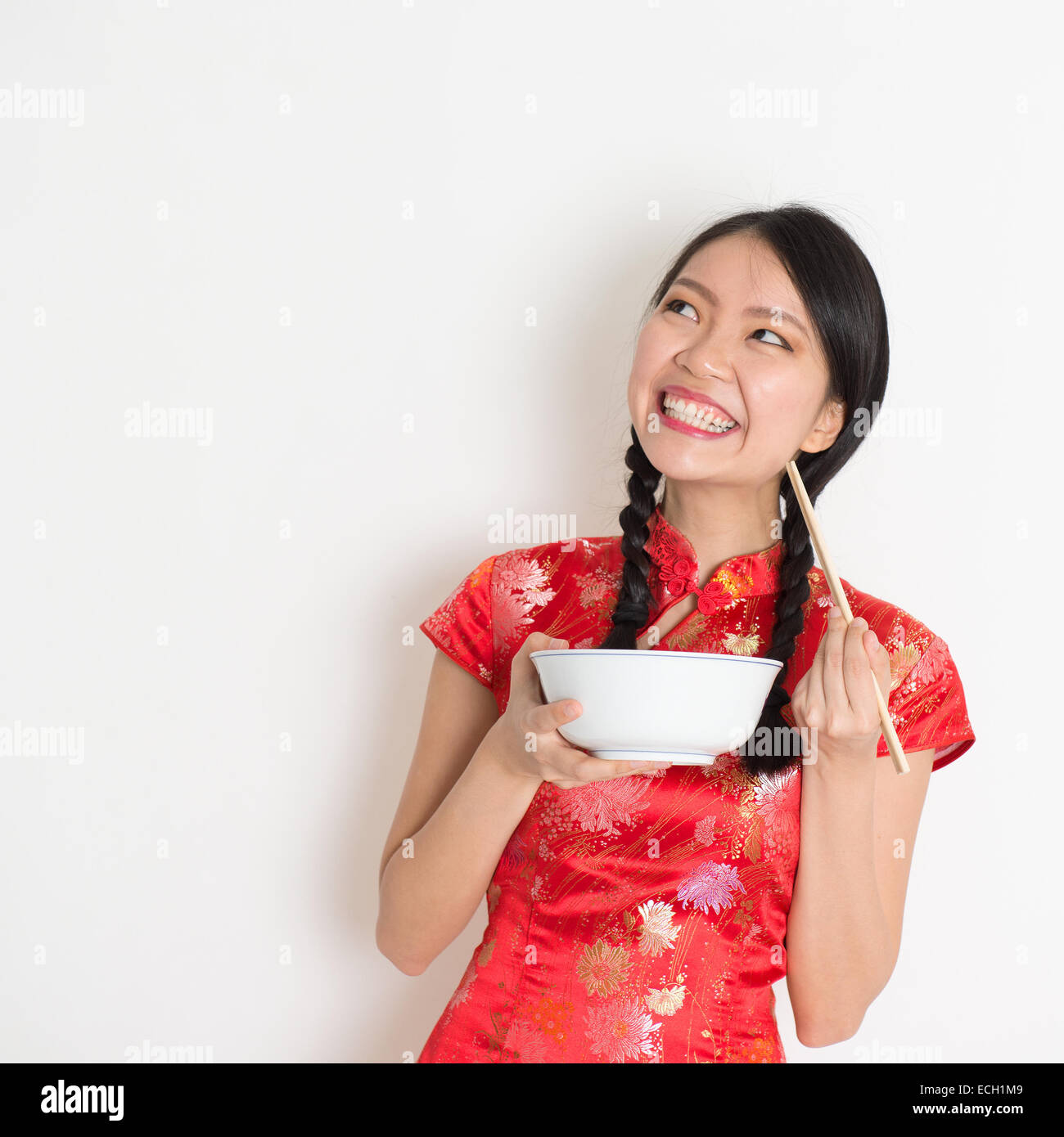 Asian Chinese female eating using chopsticks holding rice bowl, in