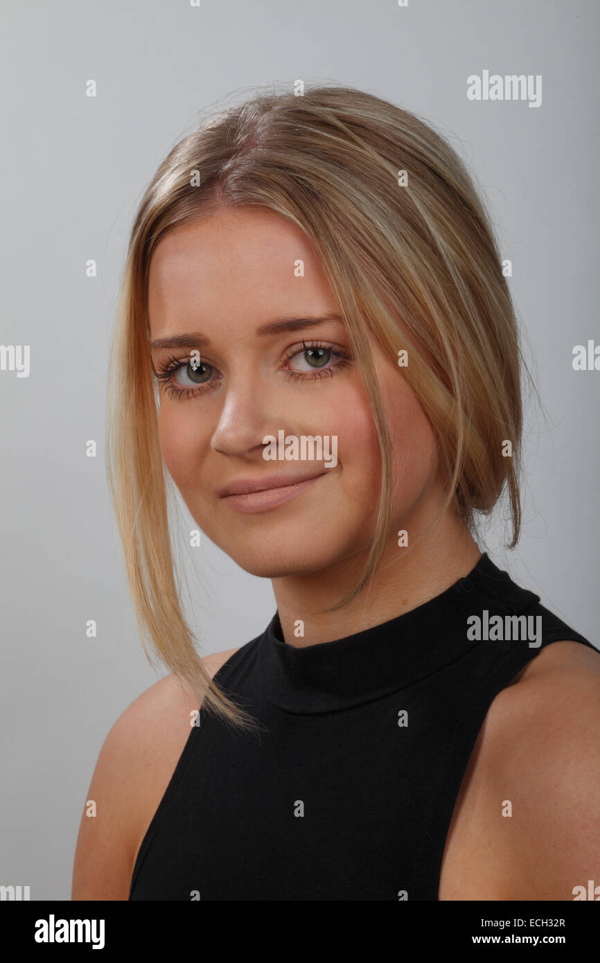 headshot or portrait of a young blonde woman with green eyes, wearing a black top and her hair up. Stock Photo