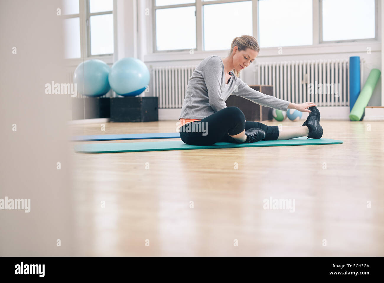 Shot of an attractive woman sitting on the floor doing exercise. Fit ...