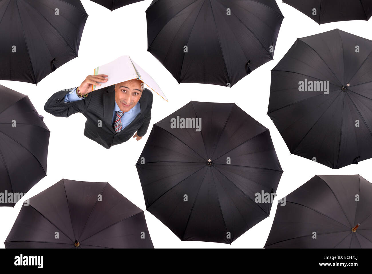 Businessman standing amongst black umbrellas isolated in white Stock
