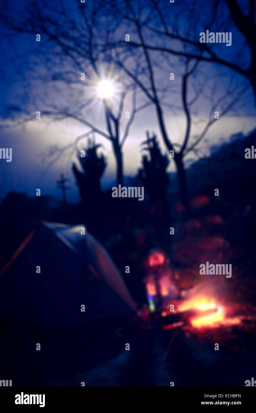 The Defocus of Camping Fire in the Cool Night with Full Moon. Stock Photo