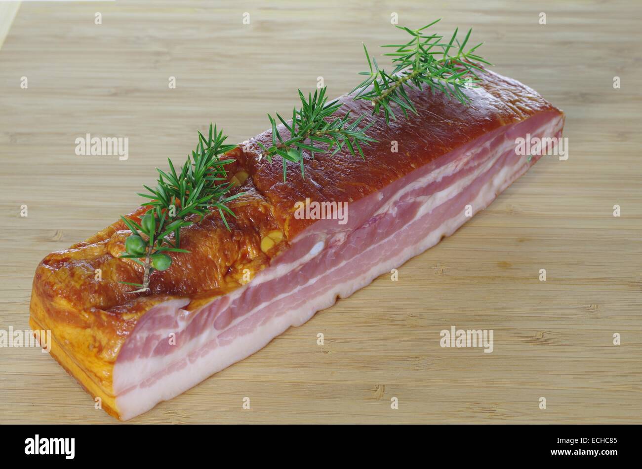 smoked bacon with juniper on chopping board Stock Photo