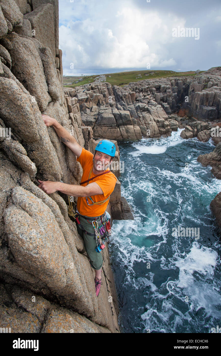 Iain Millar - a professional mountain guide - rock climbing up a sea stack near Gweedore, County Donegal, Ireland. Stock Photo