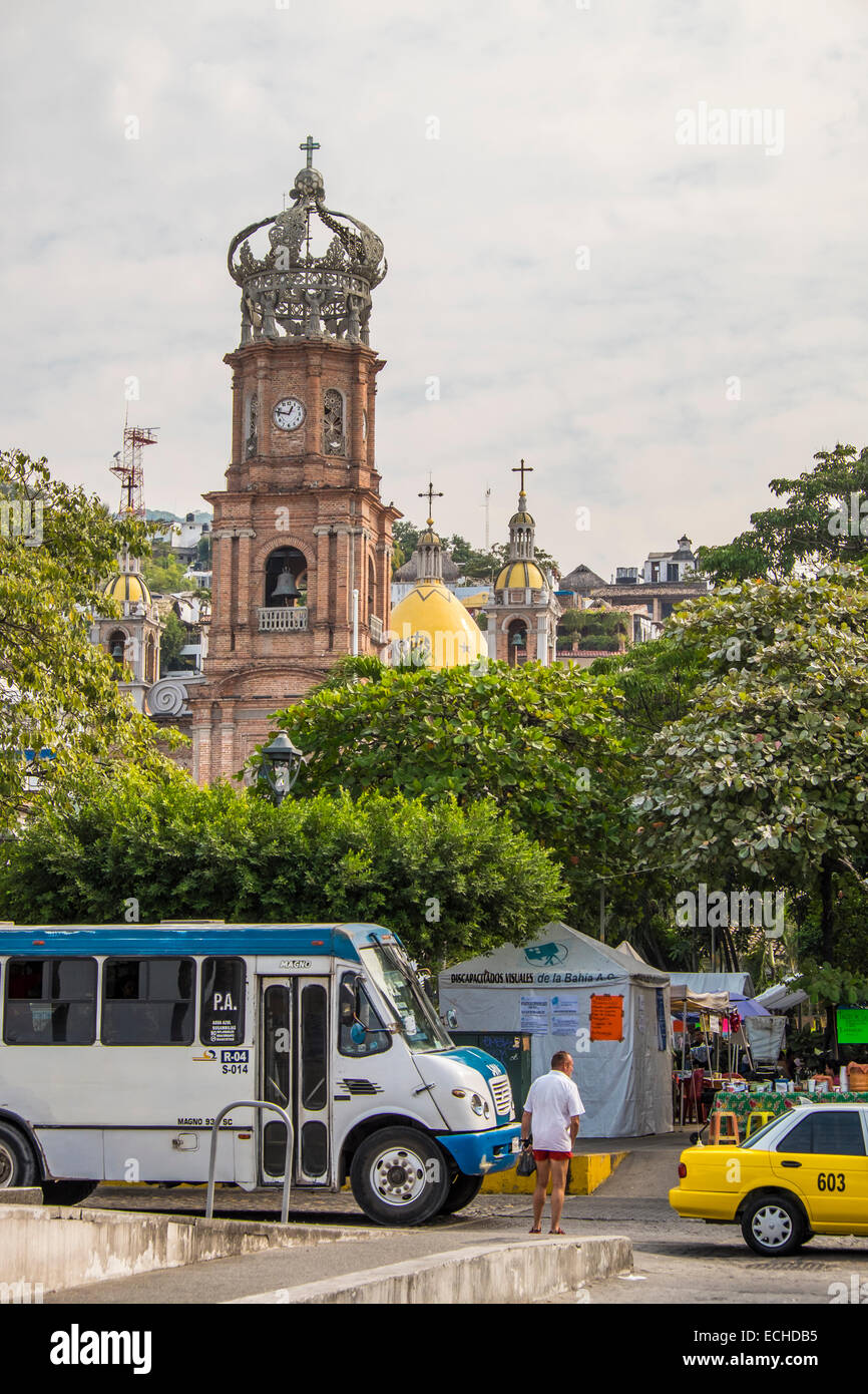 Puerto Vallarta City Center with public transportation bus traffic. Church of Our Lady of Guadalupe in the background. Stock Photo