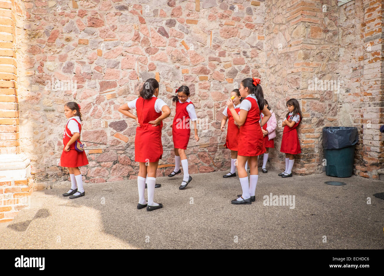 Girls in school uniform playing Chinese Jump Rope games during break. Puerto Vallarta, Mexico. Stock Photo