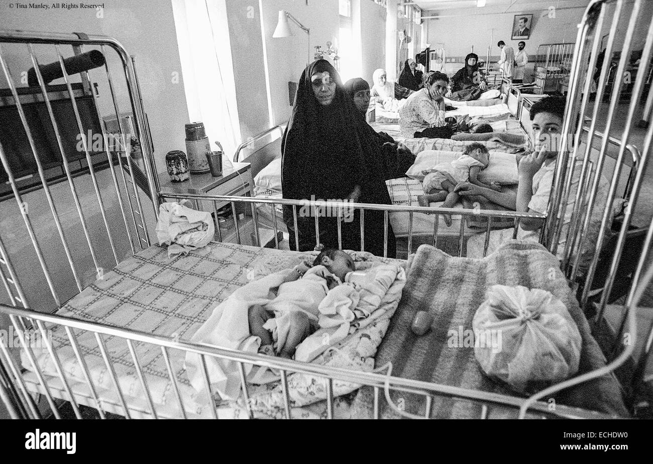 Mothers stay with their babies in the infant ward of the Saddam Hussein Children's Hospital in Baghdad, Iraq.  In 1991 UN Sanctions prevented some medicines from being imported for the hospitals.  Saddam Hussein's portrait is on the back wall. Stock Photo