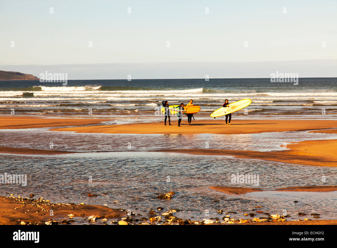 Surfers on beach leaving sea carrying surfboard surfboards walking back