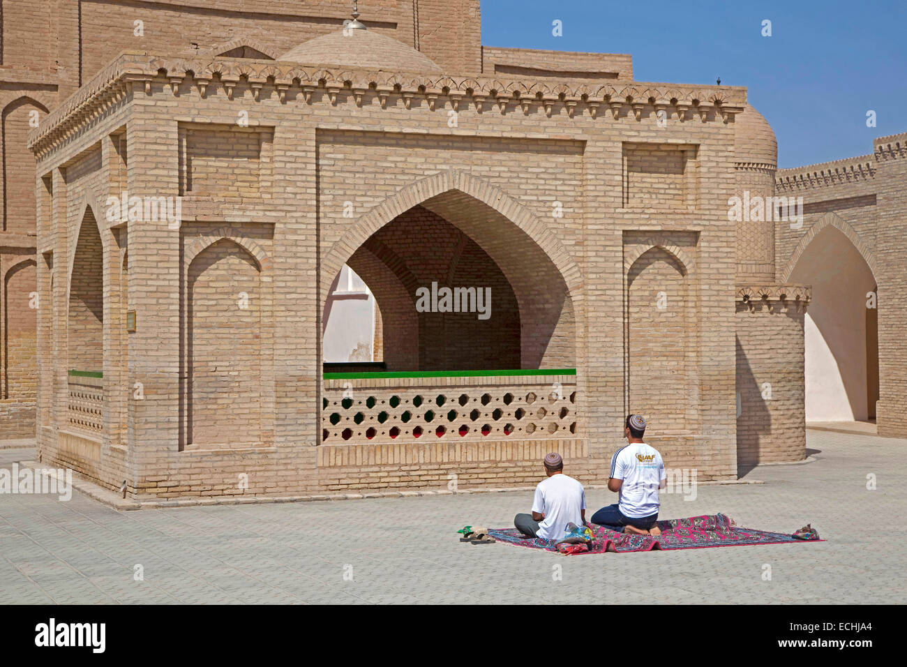 Two Turkmen praying on carpet in front of Mausoleum of Hoja Yusuf Hamadani in the city of Merv / Merw near Mary, Turkmenistan Stock Photo