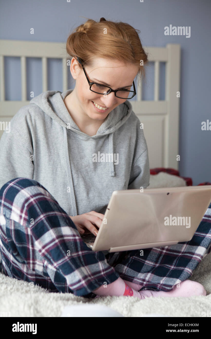 Young woman working on her laptop on the bed Stock Photo - Alamy