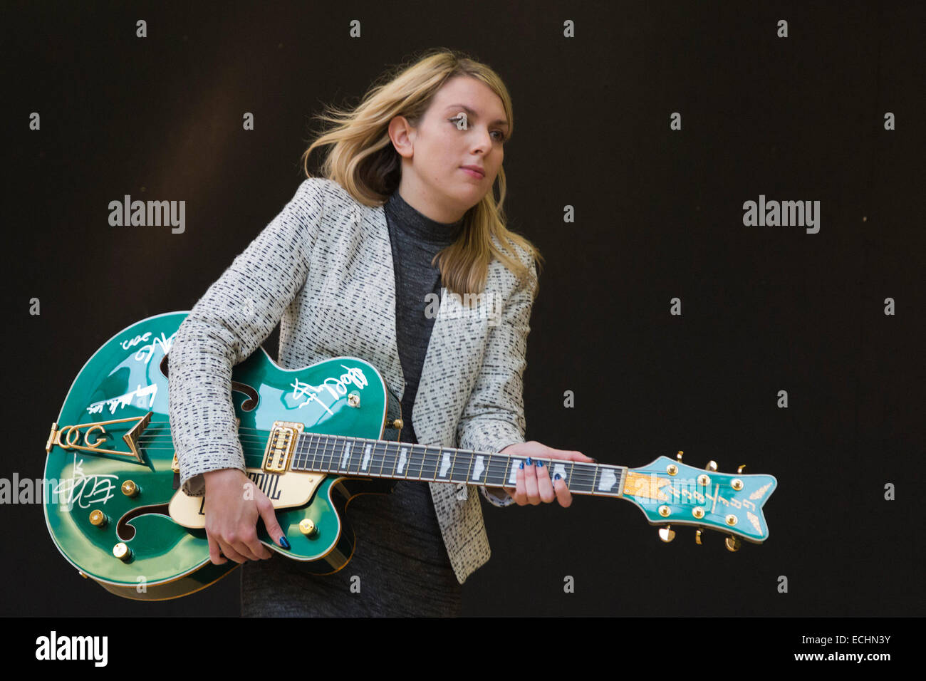 London, UK. 12 December 2014. A Christie's employee poses with Bono's custom prototype Gretsch Irish Falcon electric guitar signed by all four members of U2, estimate GBP 120,000-180,000. Christie's unveils Memorabilia of Hollywood Icons & Music Legends from the 20/21 Pop Culture Sale ahead of a free public view from 13 to 16 December 2014, with the auction taking place on 16 December. The sale celebrates some of the great names of 20th century cinema and music legends, featuring costumes and film scripts, instruments and handwritten song lyrics. Stock Photo