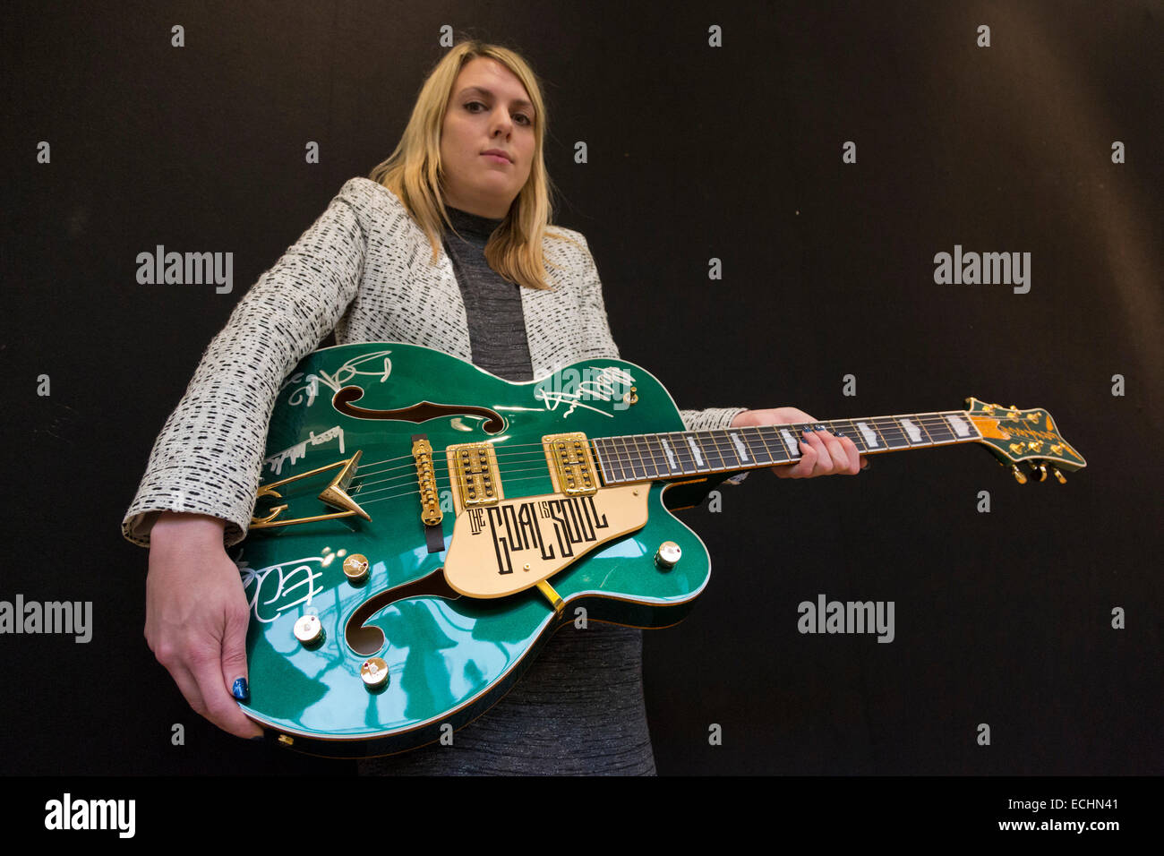 London, UK. 12 December 2014. A Christie's employee poses with Bono's custom prototype Gretsch Irish Falcon electric guitar signed by all four members of U2, estimate GBP 120,000-180,000. Christie's unveils Memorabilia of Hollywood Icons & Music Legends from the 20/21 Pop Culture Sale ahead of a free public view from 13 to 16 December 2014, with the auction taking place on 16 December. The sale celebrates some of the great names of 20th century cinema and music legends, featuring costumes and film scripts, instruments and handwritten song lyrics. Stock Photo