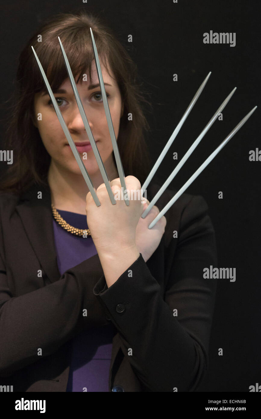 London, UK. 12 December 2014. A Christie's employee poses with a rare pair of 'adamantium' claws made for Hugh Jackman as Wolverine in the 2006 film X-Men: The Last Stand, estimate: GBP 10,000-15,000. Christie's unveils Memorabilia of Hollywood Icons & Music Legends from the 20/21 Pop Culture Sale ahead of a free public view from 13 to 16 December 2014, with the auction taking place on 16 December. The sale celebrates some of the great names of 20th century cinema and music legends, featuring costumes and film scripts, instruments and handwritten song lyrics. Stock Photo
