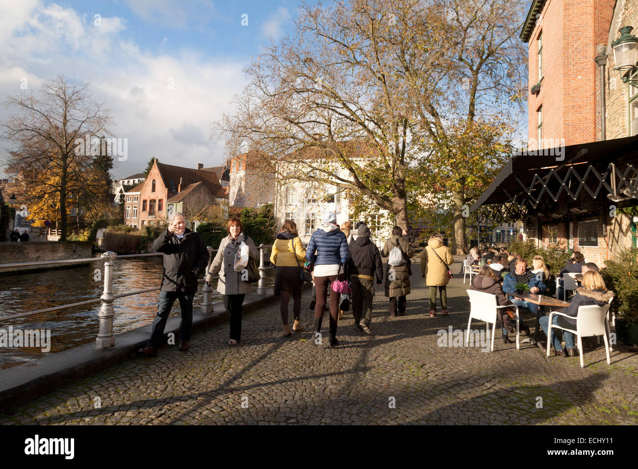 people walking on cobblestones beside the canal in autumn, Bruges, Belgium, Europe Stock Photo