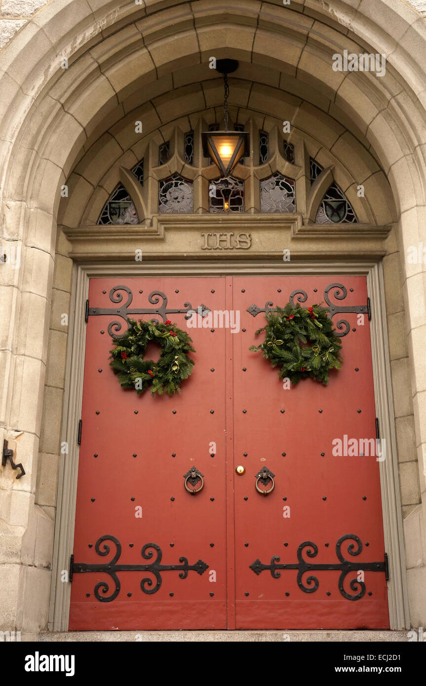 Traditional green and red Christmas wreath hanging on the door of the