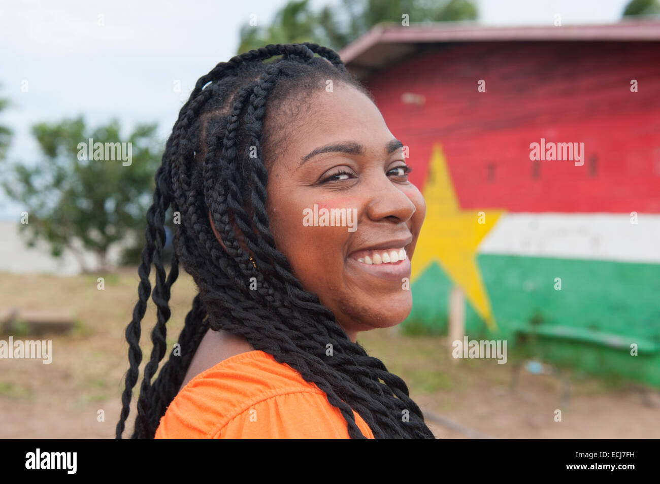Arlette, a Surinamese girl with dreadlocks, in front of the Surinamese flag painted on a wall at Christiaankondre, Galibi Stock Photo