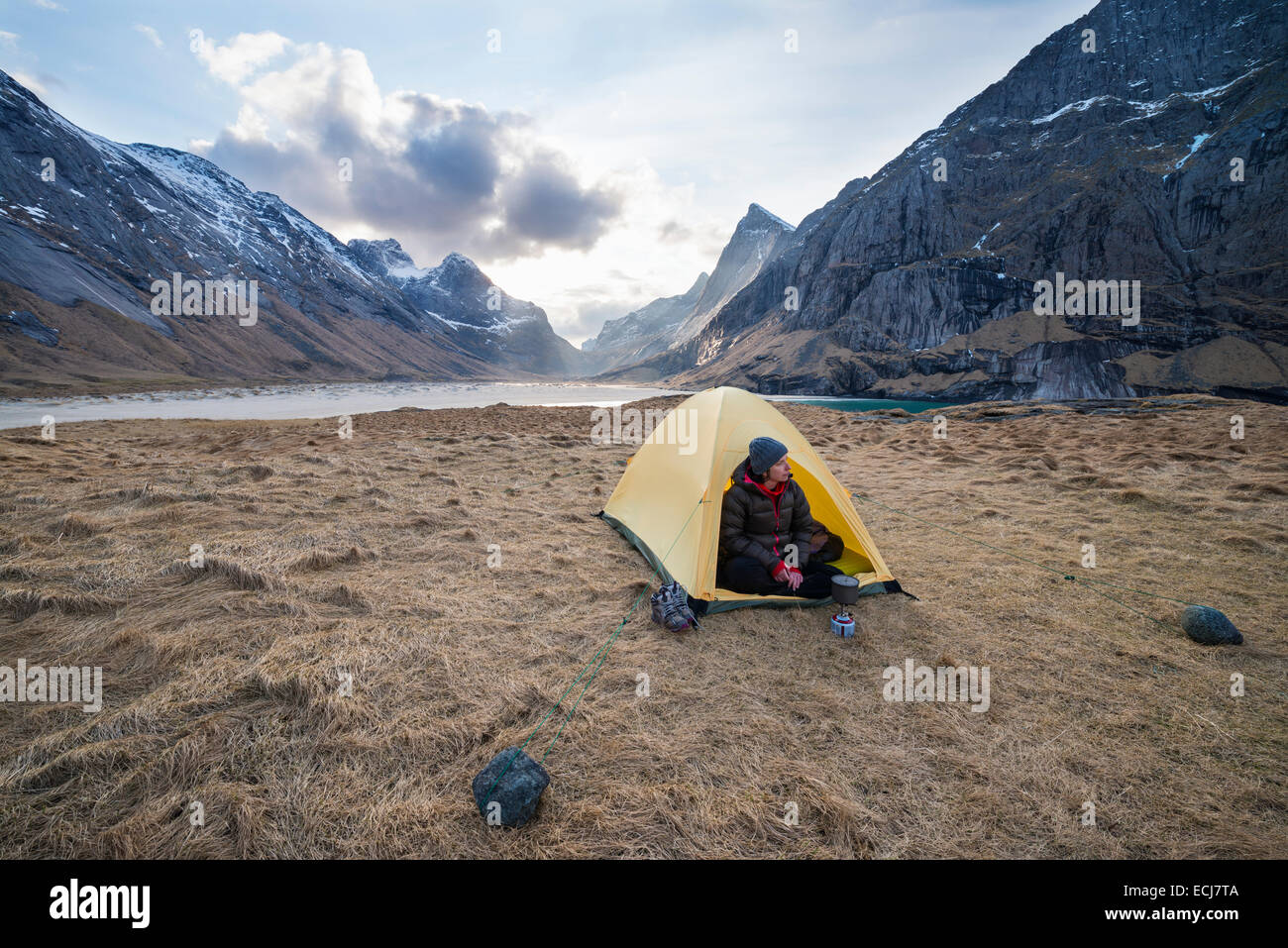 Female backpacker takes in view from tent while camping at Horseid beach, Moskenesøy, Lofoten Islands, Norway Stock Photo